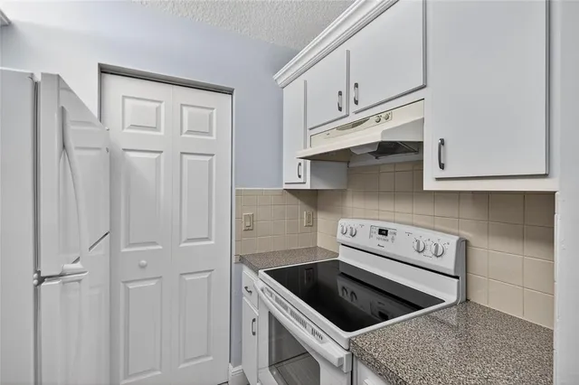 a kitchen with stainless steel appliances granite countertop white cabinets and a stove