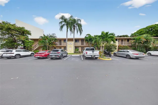 a view of road with card parked on side and retail shops