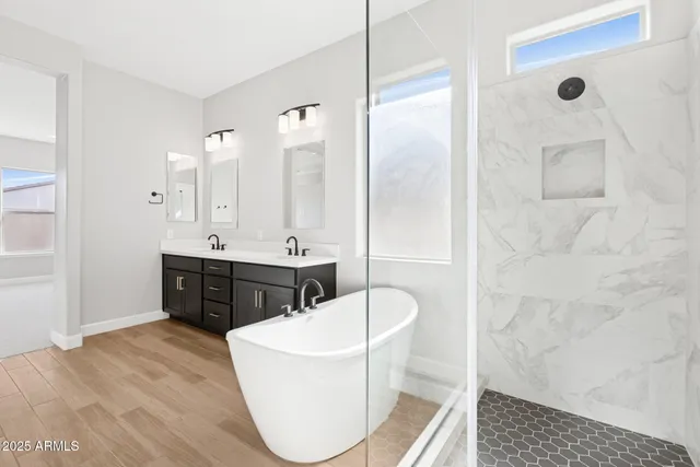 a spacious bathroom with a double vanity sink a mirror and a bathtub