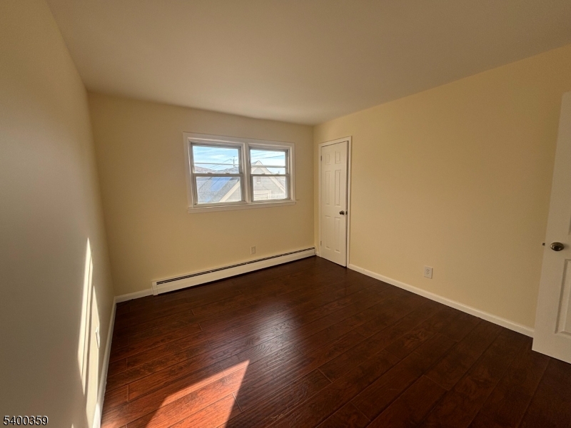 119 Church Street Lodi, NJ 07644 - Photo 4 of 8 an empty room with wooden floor and windows