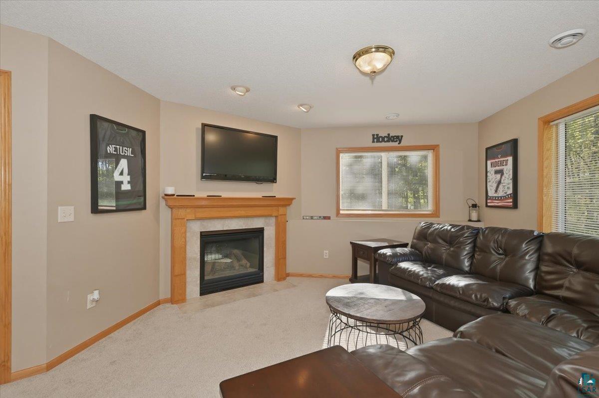 47 Amy Lane Esko, MN 55733 - Photo 8 of 33 Living area featuring a gas fireplace with a wood mantle and tile surround, recessed lighting, and carpet flooring
