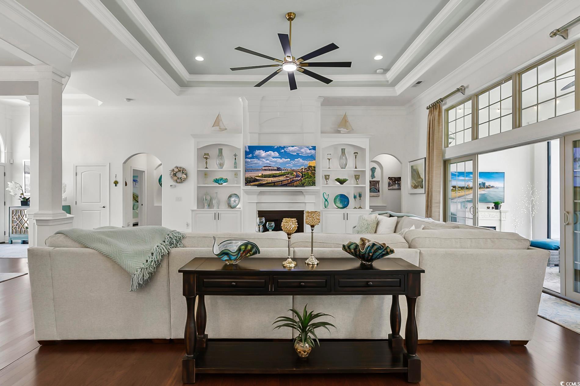 4000 Girvan Drive Myrtle Beach, SC 29579 - Photo 12 of 40 Living area featuring arched walkways, wood finished floors, ornamental molding, a raised ceiling, and ornate columns