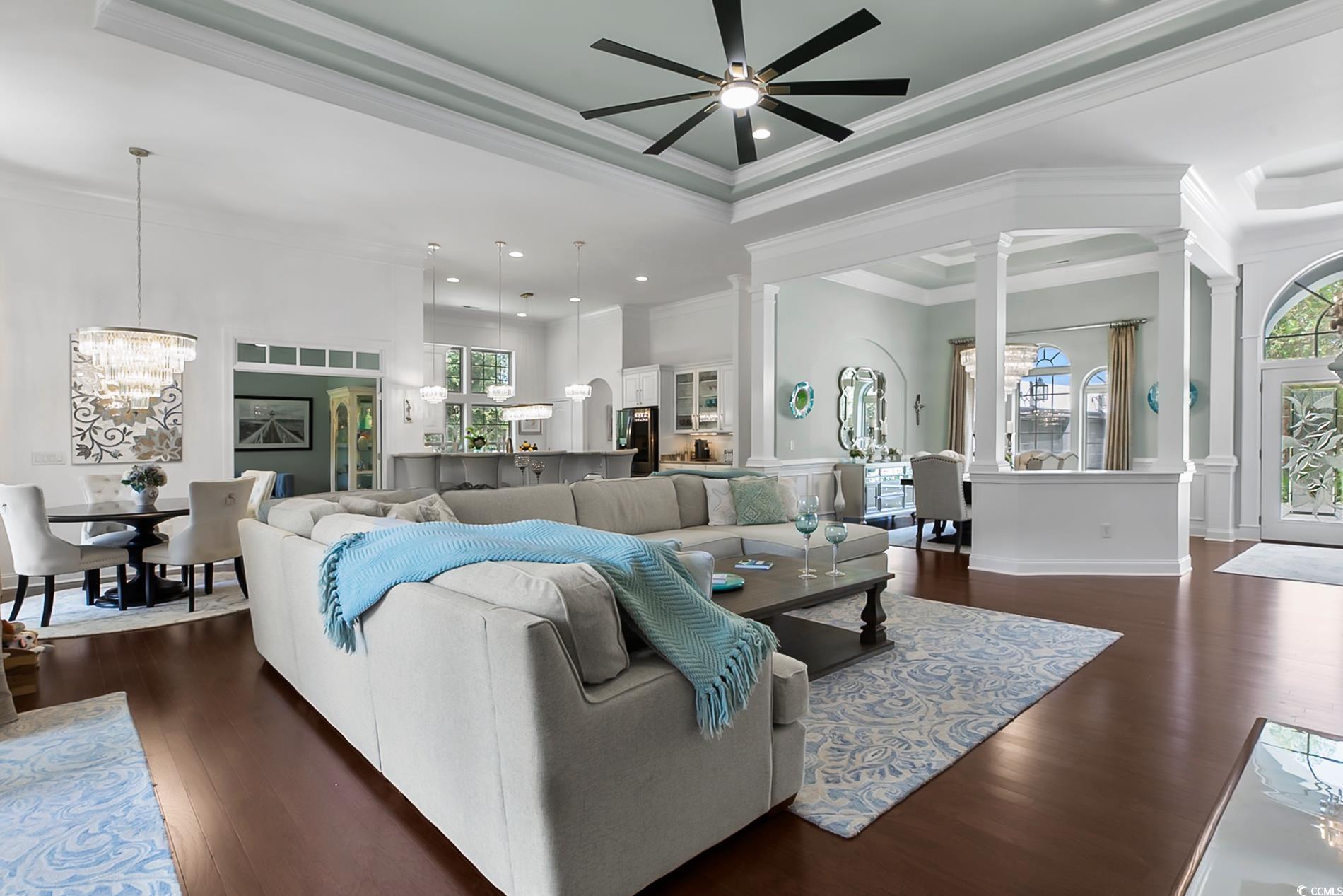 4000 Girvan Drive Myrtle Beach, SC 29579 - Photo 14 of 40 Living room featuring a chandelier, a raised ceiling, dark wood-type flooring, crown molding, and a ceiling fan