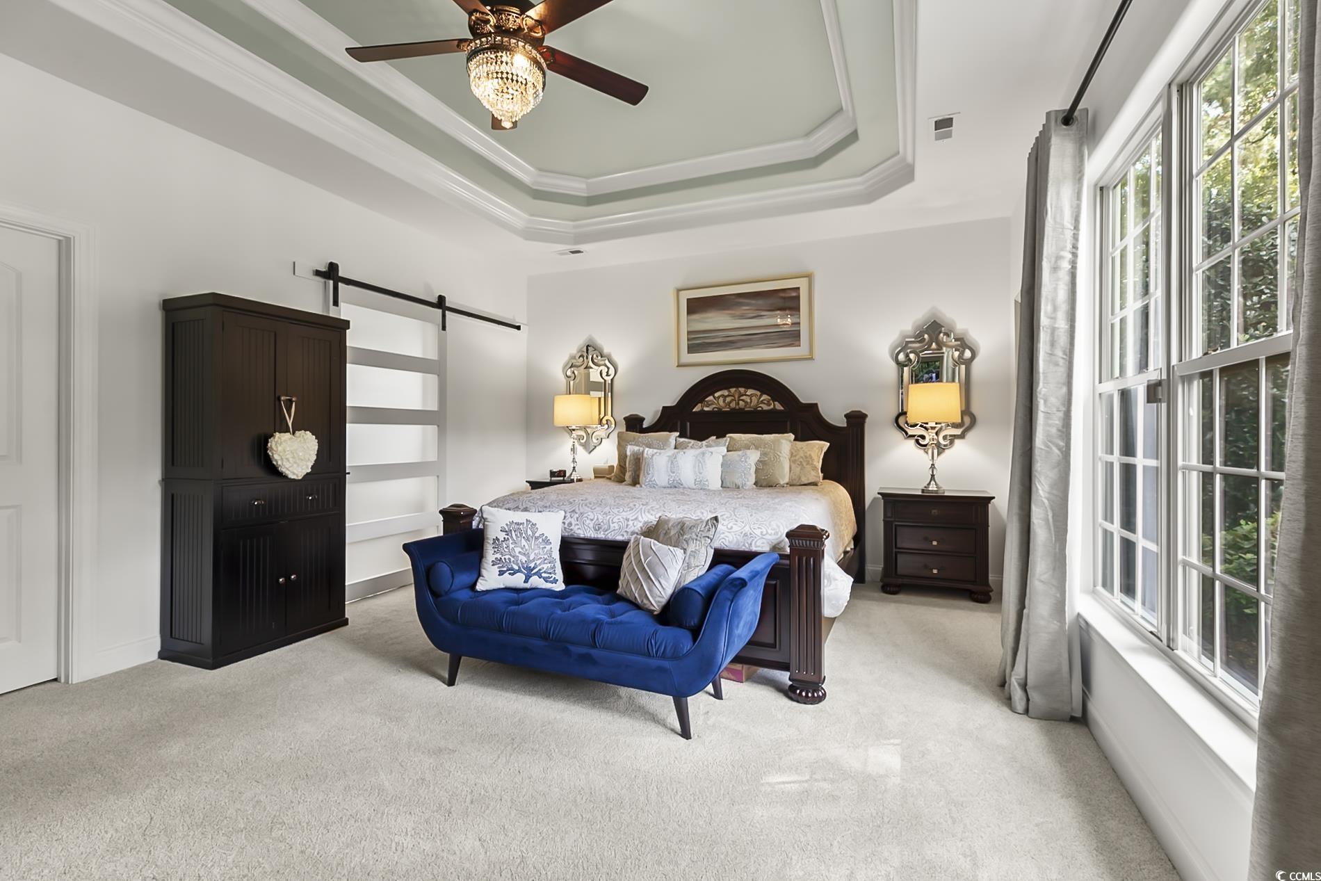 4000 Girvan Drive Myrtle Beach, SC 29579 - Photo 24 of 40 Bedroom featuring a barn door, carpet, a tray ceiling, crown molding, and a ceiling fan