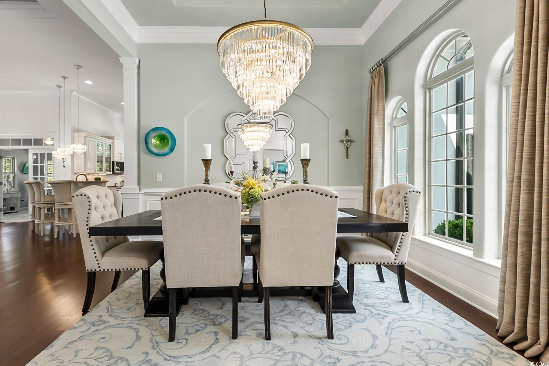 4000 Girvan Drive Myrtle Beach, SC 29579 - Photo 7 of 40 Dining room featuring a chandelier, dark wood-style flooring, crown molding, wainscoting, and a decorative wall