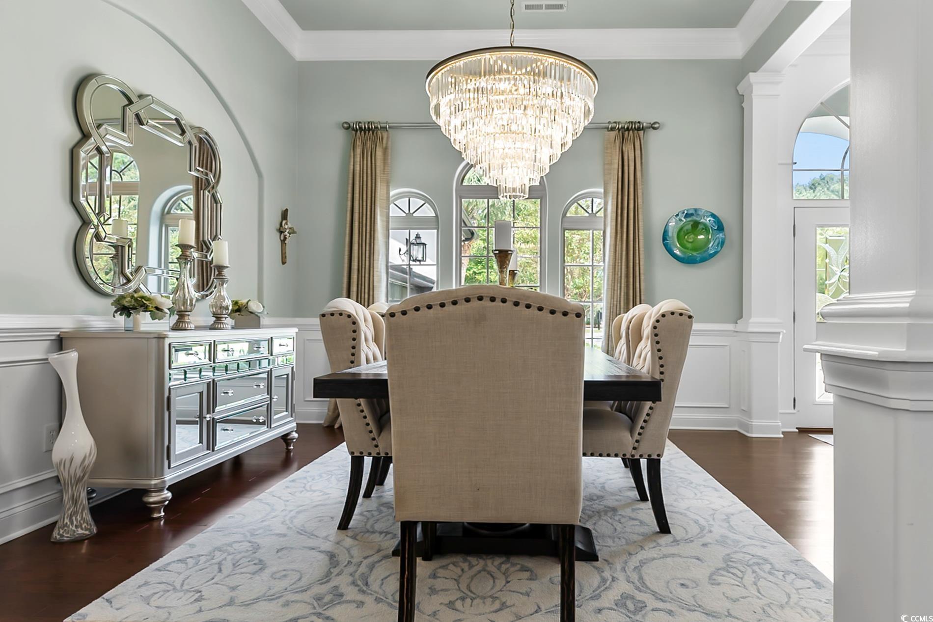 4000 Girvan Drive Myrtle Beach, SC 29579 - Photo 8 of 40 Dining space featuring a decorative wall, a wainscoted wall, crown molding, dark wood-style floors, and healthy amount of natural light