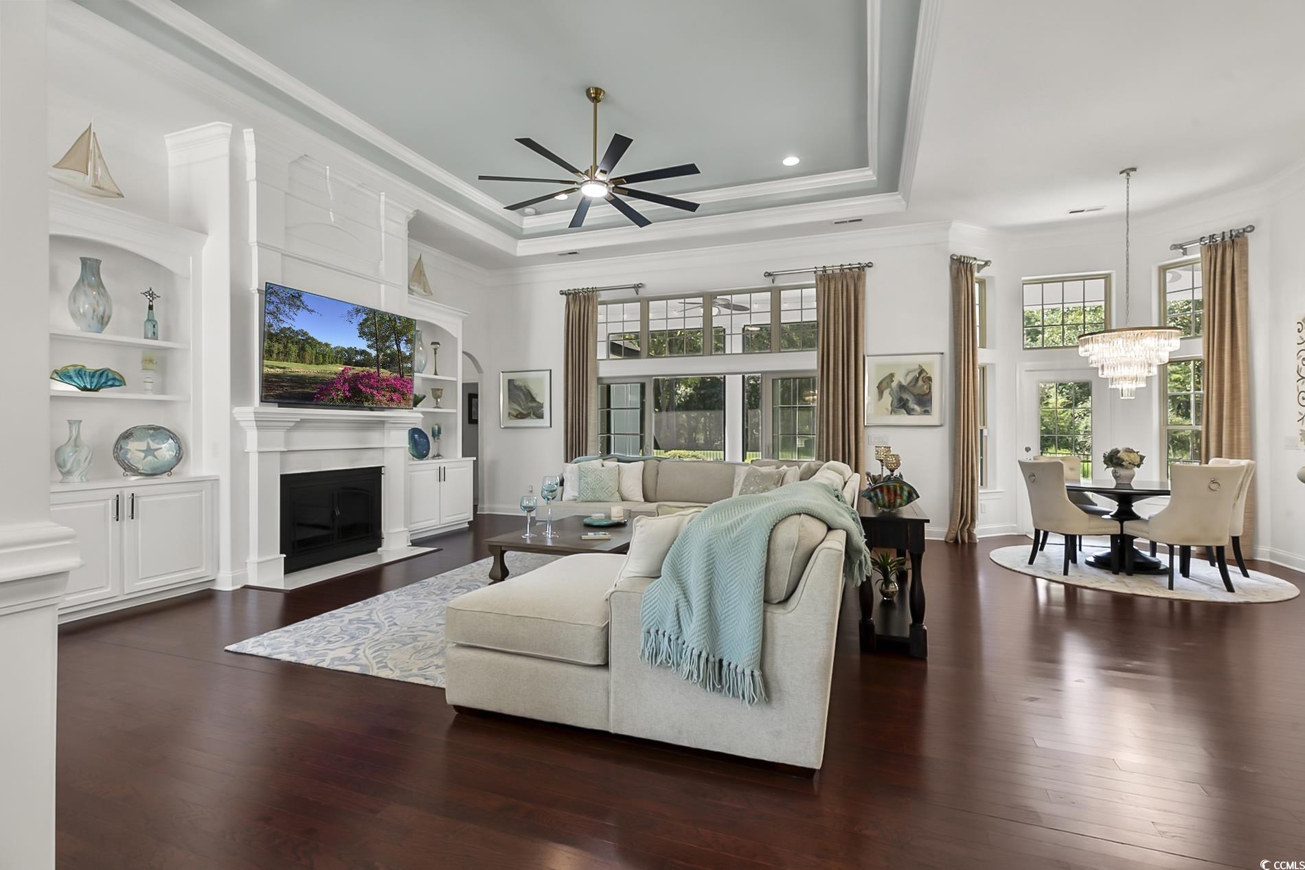 4000 Girvan Drive Myrtle Beach, SC 29579 - Photo 10 of 40 Living area featuring a raised ceiling, dark wood-style floors, crown molding, a fireplace with flush hearth, and a ceiling fan