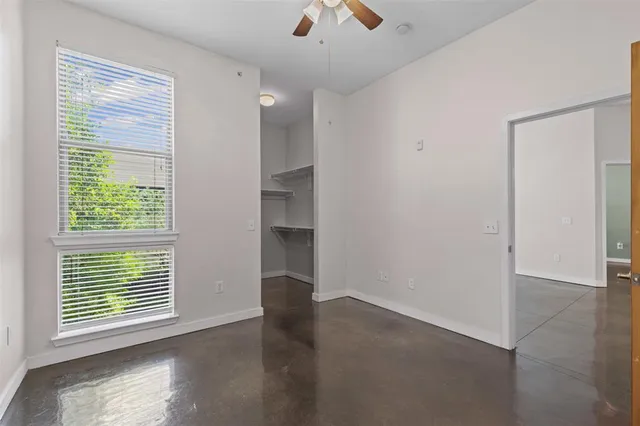 a view of an empty room with a window and a kitchen