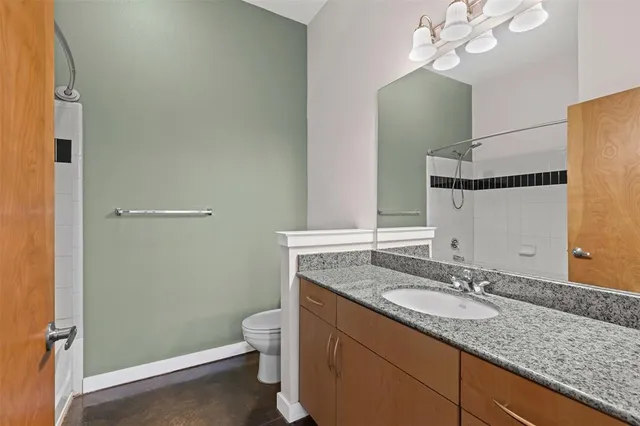 a bathroom with a granite countertop sink a toilet and a mirror