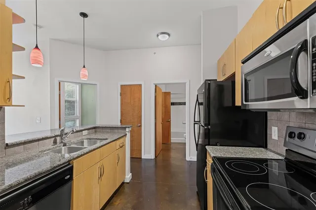 a kitchen with stainless steel appliances granite countertop a sink stove and refrigerator