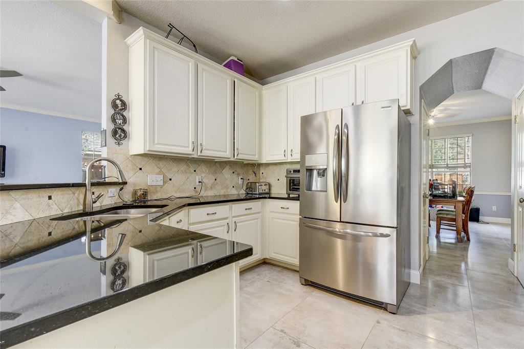 1909 Springwater Drive Round Rock, TX 78681 - Photo 14 of 34 Kitchen with stainless steel fridge with ice dispenser, crown molding, dark stone countertops, white cabinets, and tasteful backsplash