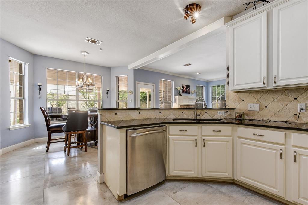 1909 Springwater Drive Round Rock, TX 78681 - Photo 18 of 34 Kitchen with dishwasher, backsplash, a chandelier, white cabinetry, and a peninsula