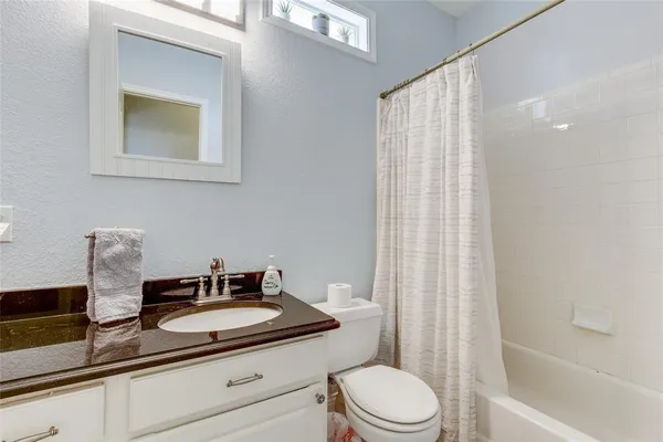 a bathroom with a granite countertop sink toilet a mirror and shower