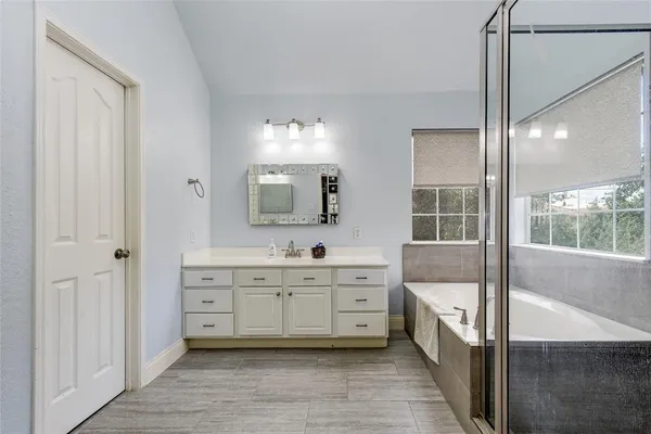 a spacious bathroom with a double vanity sink a mirror and a bathtub