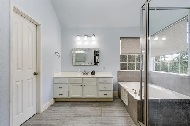 a spacious bathroom with a double vanity sink a mirror and a bathtub