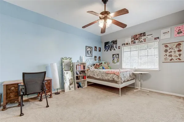 a bedroom with a bed a desk and chair with a bookshelf