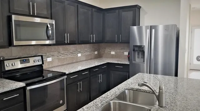 a kitchen with granite countertop a refrigerator stove and microwave