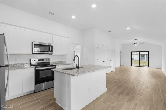 a kitchen with stainless steel appliances granite countertop a sink stove oven and white cabinets with wooden floor