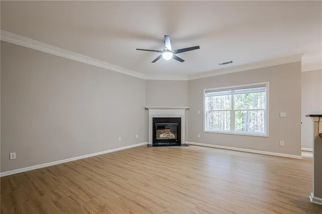an empty room with large windows fireplace and wooden floor
