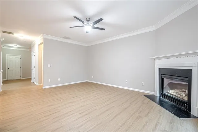 a view of an empty room with wooden floor fireplace and a window