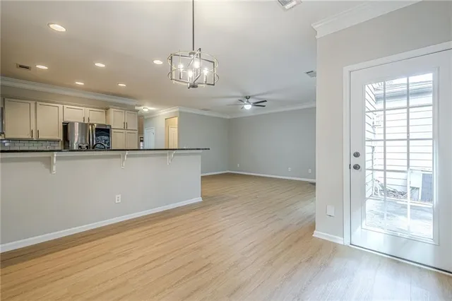 a view of a kitchen with stainless steel appliances granite countertop a refrigerator a sink dishwasher a stove and white cabinets with wooden floor