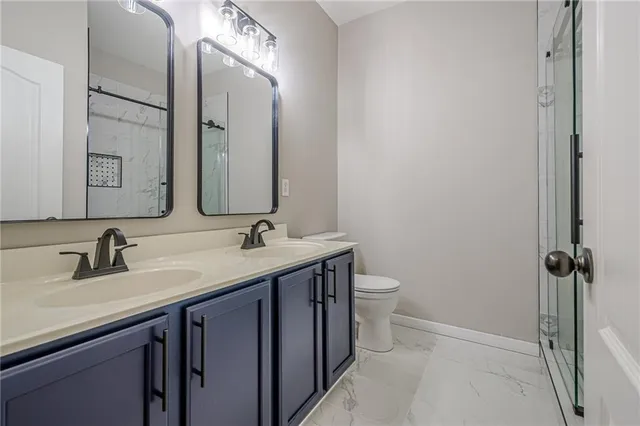a bathroom with a double vanity sink toilet and mirror