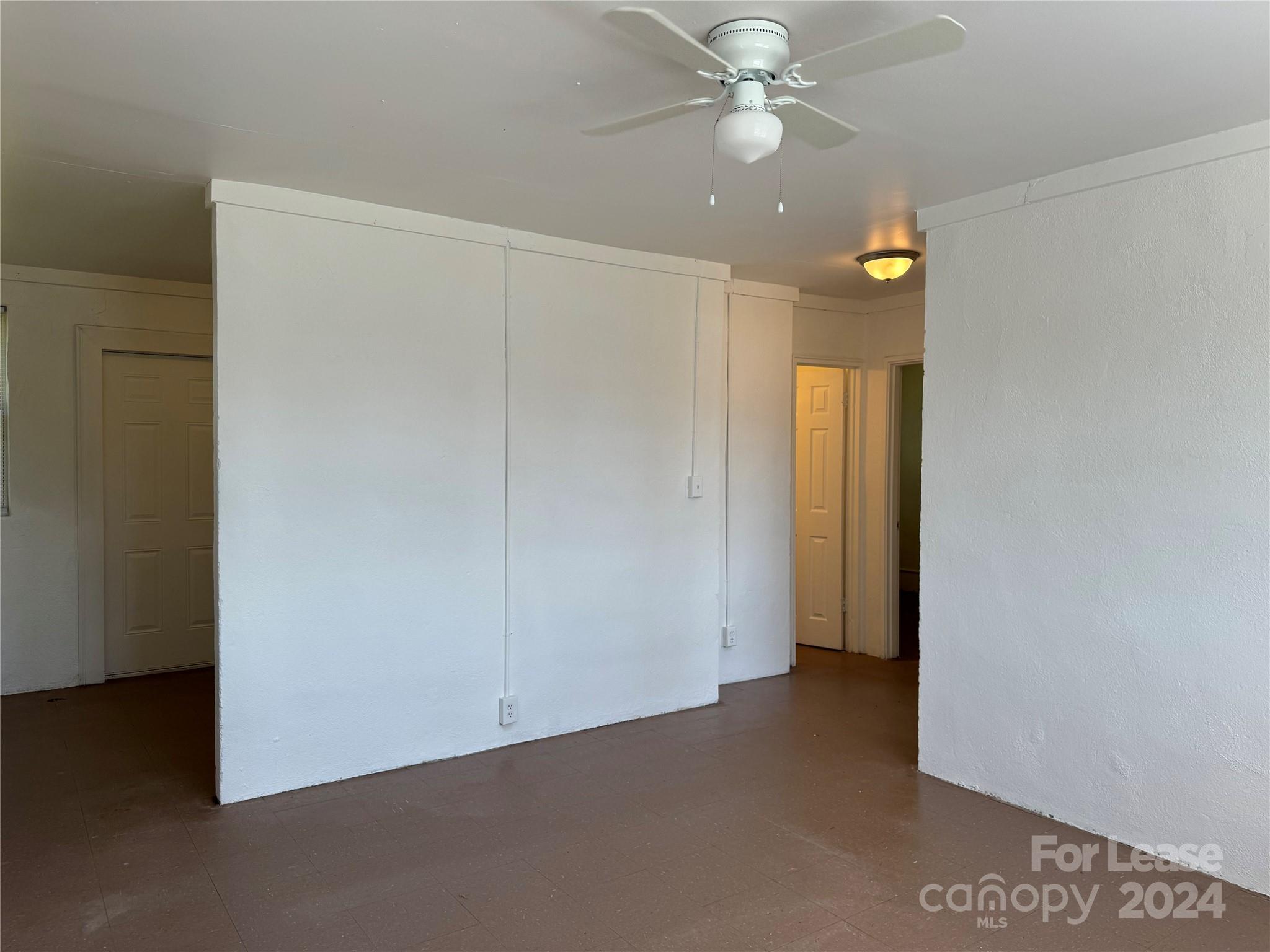 an empty room with closet and a chandelier fan