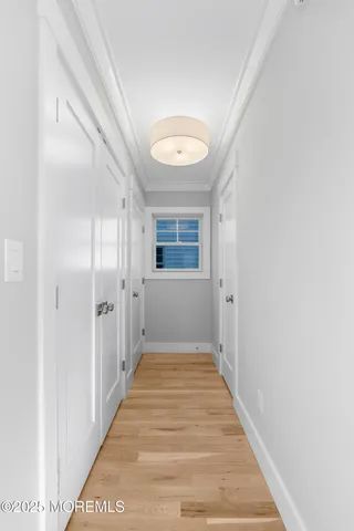 a view of a hallway with wooden floor and a bathroom