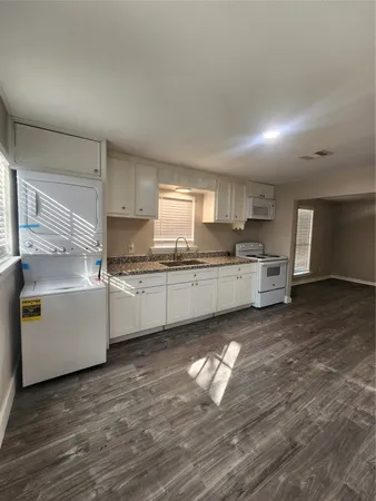a kitchen with granite countertop a sink cabinets stainless steel appliances and window