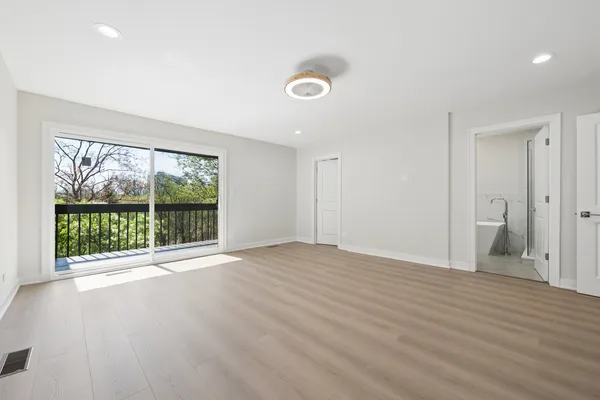a view of an empty room with a window and wooden floor