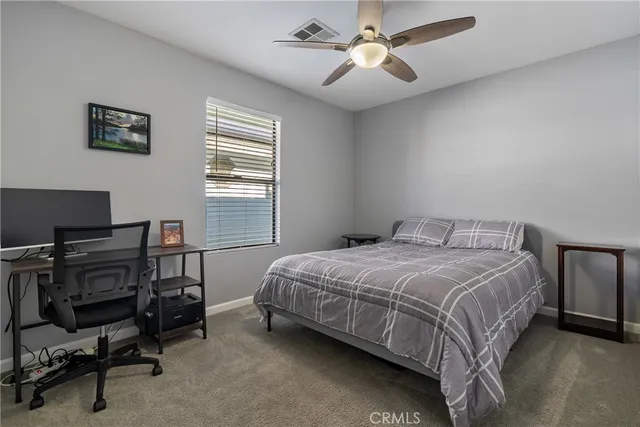 a bedroom with a bed a computer on a desk and chair