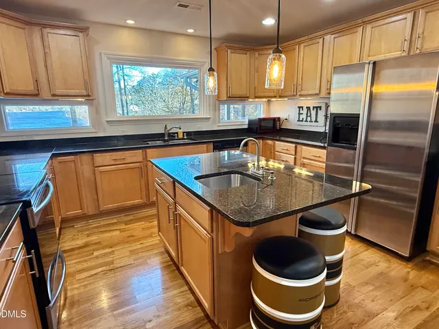 a kitchen with kitchen island granite countertop a sink a counter space stainless steel appliances and cabinets