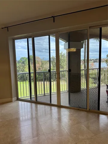 a view of an empty room with window and chandelier fan