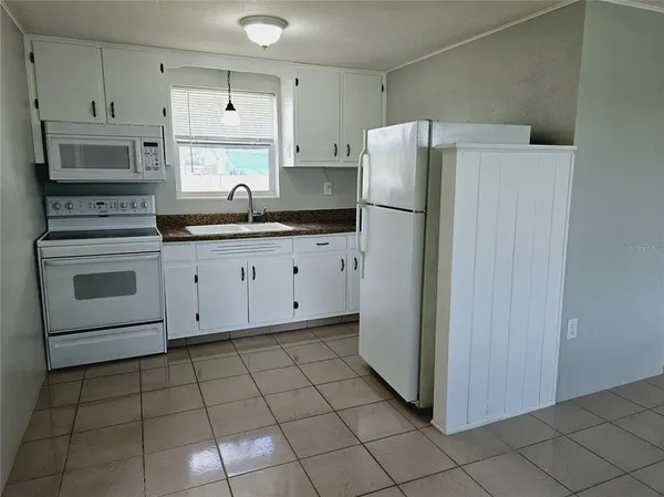 a kitchen with granite countertop a refrigerator sink and cabinets