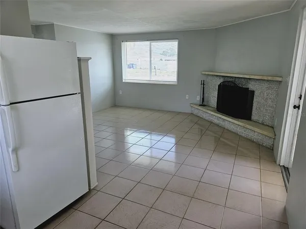 a view of a refrigerator in kitchen and an empty room in wooden floor