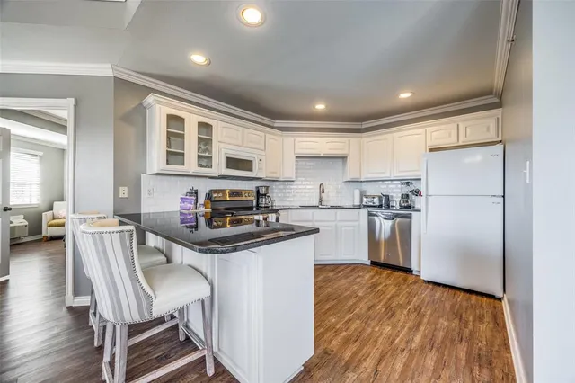 a kitchen with kitchen island a counter top space a sink stainless steel appliances and cabinets