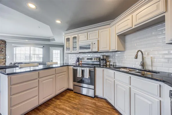a kitchen with granite countertop white cabinets sink and stainless steel appliances