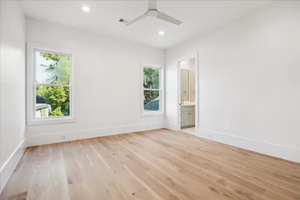 an empty room with wooden floor cabinet and windows