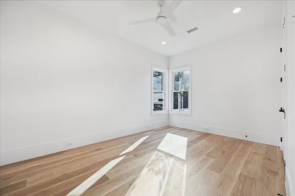 an empty room with wooden floor and windows