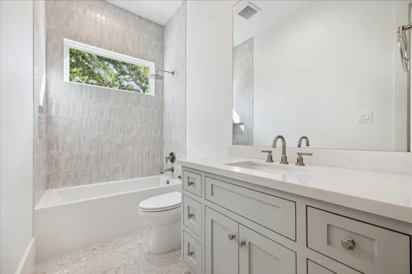 a bathroom with a granite countertop sink a toilet and a bathtub