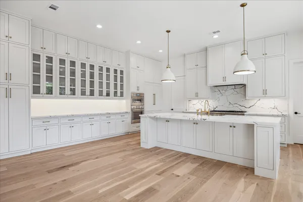 a large kitchen with granite countertop a white stove top oven and white cabinets