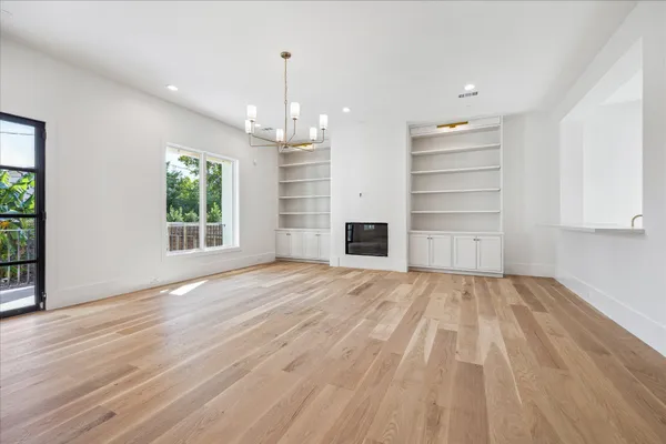 a view of empty room with wooden floor and window