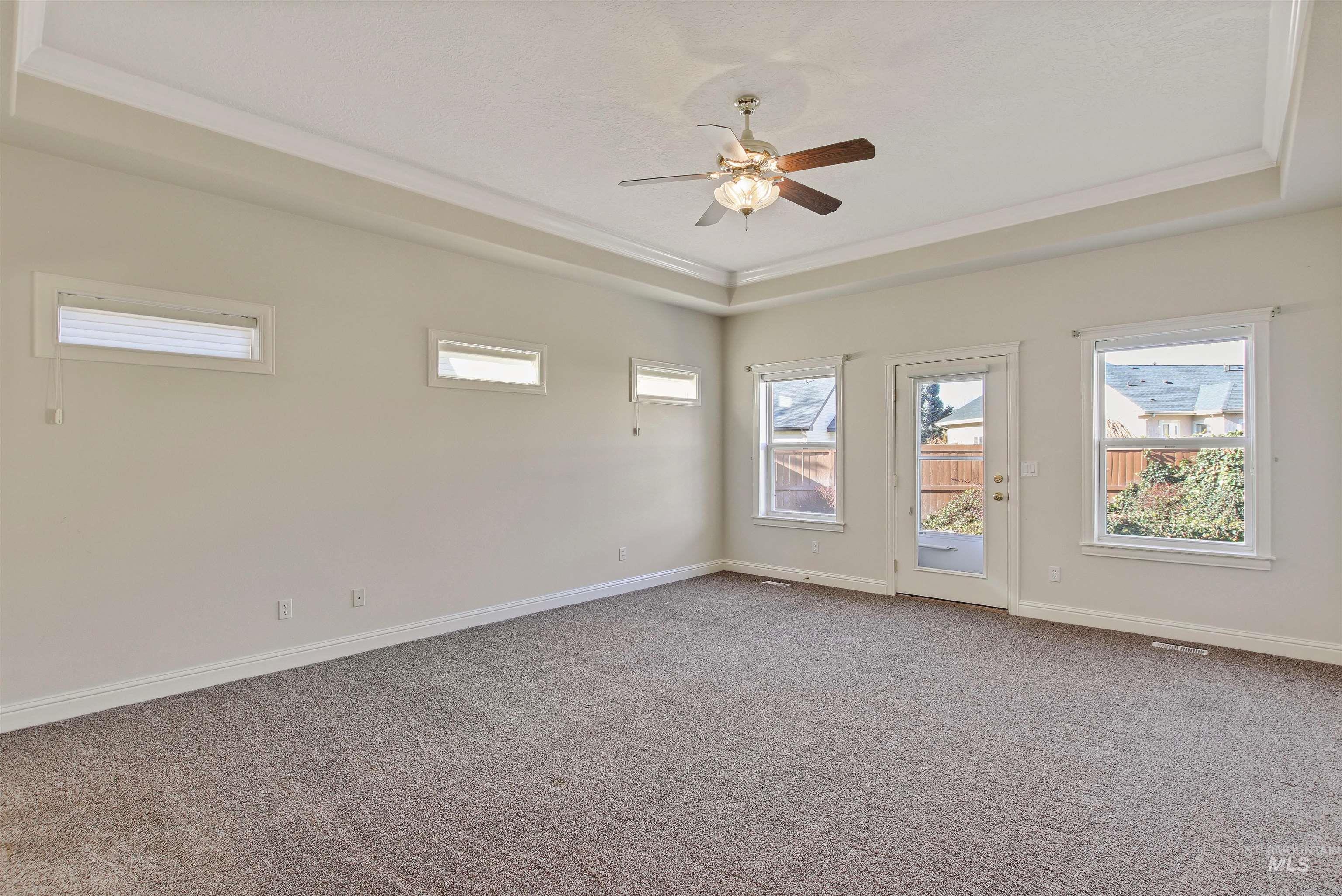 2297 North Chandra Way Meridian, ID 83646 - Photo 28 of 49 Empty room featuring a tray ceiling, light carpet, healthy amount of natural light, a ceiling fan, and crown molding