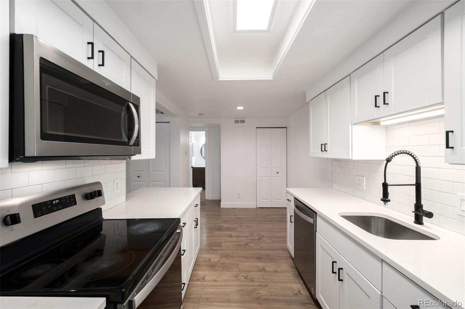 2929 West Floyd Avenue, Unit 201 Denver, CO 80236 - Photo 11 of 28 a kitchen with stainless steel appliances a stove microwave sink and cabinets