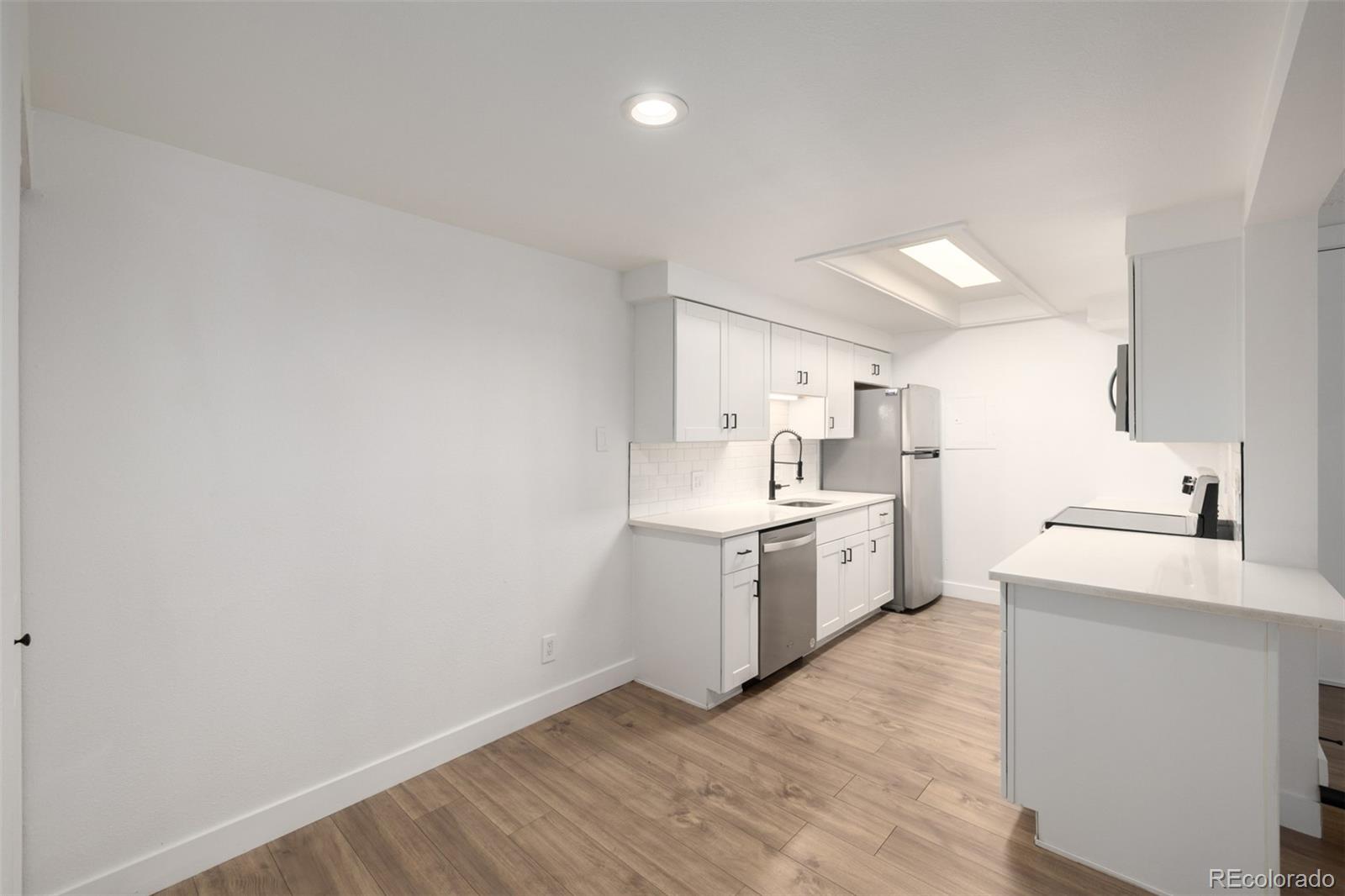 2929 West Floyd Avenue, Unit 201 Denver, CO 80236 - Photo 13 of 28 a kitchen with a sink cabinets stainless steel appliances and a window