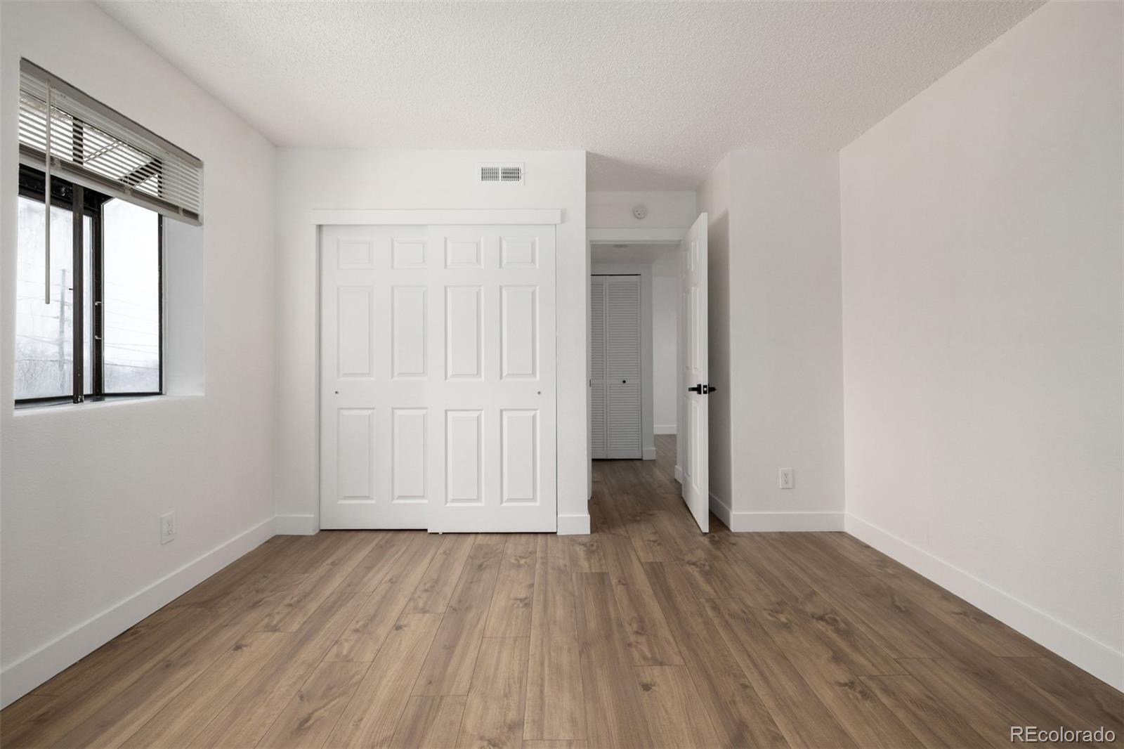 2929 West Floyd Avenue, Unit 201 Denver, CO 80236 - Photo 19 of 28 an empty room with wooden floor and windows