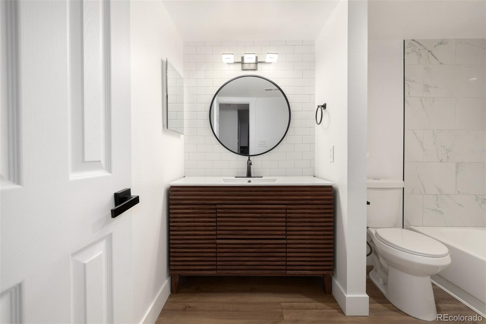 2929 West Floyd Avenue, Unit 201 Denver, CO 80236 - Photo 21 of 28 a bathroom with a toilet a sink and a mirror