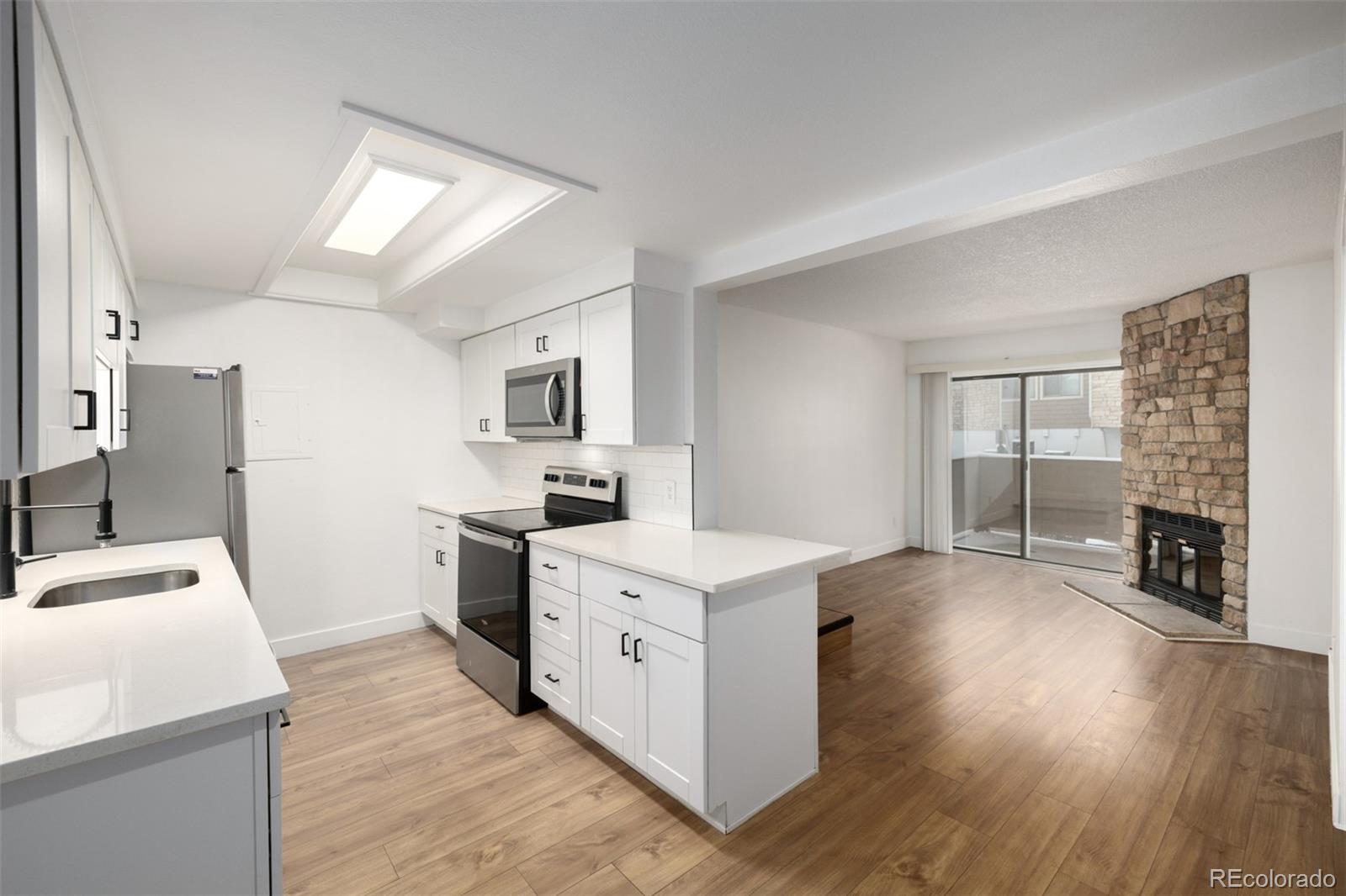 2929 West Floyd Avenue, Unit 201 Denver, CO 80236 - Photo 8 of 28 a view of a kitchen with fridge and wooden floor