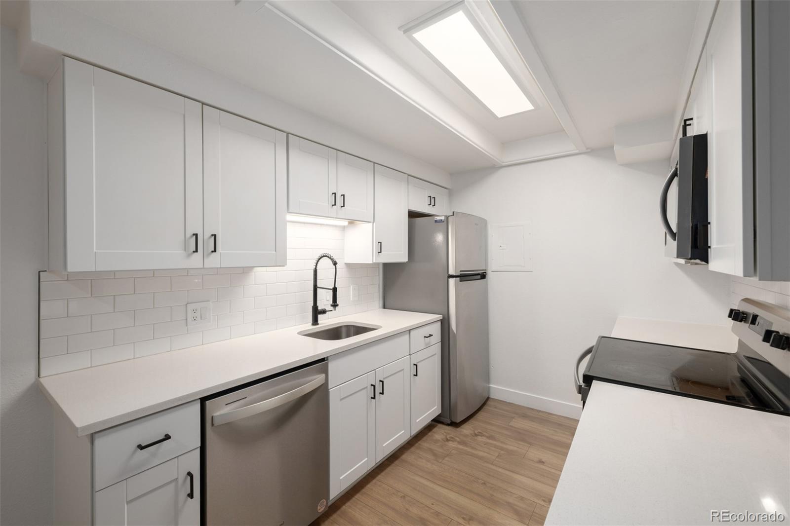 2929 West Floyd Avenue, Unit 201 Denver, CO 80236 - Photo 9 of 28 a kitchen with stainless steel appliances a sink a refrigerator and a stove
