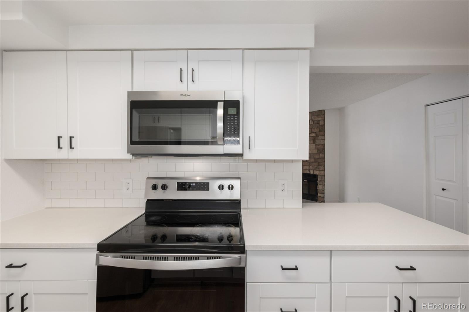 2929 West Floyd Avenue, Unit 201 Denver, CO 80236 - Photo 10 of 28 a kitchen with stainless steel appliances a stove a microwave and cabinets